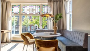 A modern room with a round table, two chairs, a sofa, and a large window with stained glass. - Beautiful apartment, view of Delft canal. (Delft)
