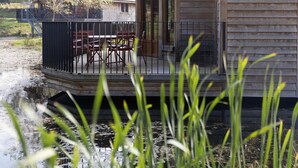 Uma casa flutuante com deck, cadeiras e uma mesa.