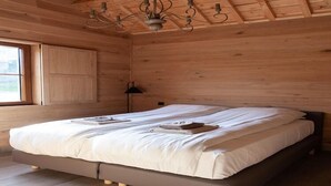 Quarto de cabana de madeira com uma cama grande, uma janela e um candelabro.