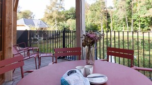 A covered patio with a table set for two, a vase with dried flowers, and a bag of snacks. - Escape to Nature in Vencimont (Vencimont)