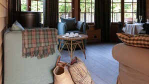 A cozy room with a sofa, a table with cups and a glass, and a view of greenery through large windows. - Escape to Nature in Vencimont (Vencimont)