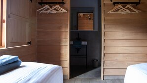 A wooden room with two beds, a small bathroom, and a hanging clothes rack. - Escape to Nature in Vencimont (Vencimont)