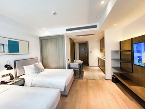 Ein modernes Hotelzimmer mit zwei Betten, einem Fernseher und einer Küchenzeile.
