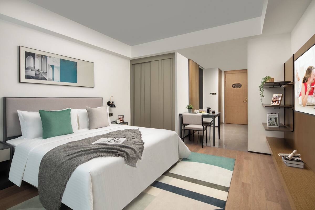 Una habitación de hotel moderna con una cama grande, un escritorio y un rincón de comedor.