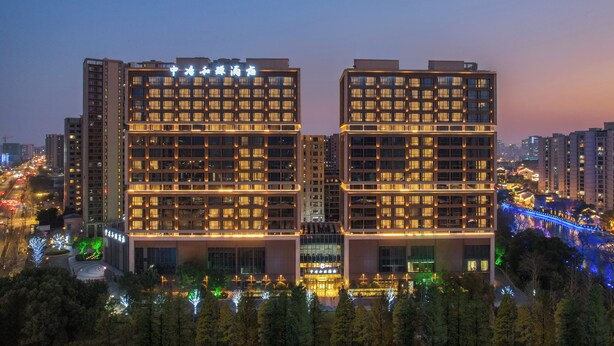 A modern hotel with a symmetrical facade, multiple floors, and illuminated windows. - MCC Hotel Hangzhou Grand Canal (Hangzhou)