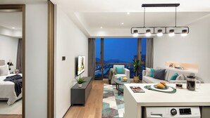 A modern apartment with a living area, kitchen, and bedroom. It features a large window with a city view, a dining area with a table and chairs, and a built-in washing machine. - MCC Hotel Hangzhou Grand Canal (Hangzhou)