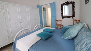A bedroom with a bed, two chairs, a wardrobe, and a mirror. - Villa Camilla in Otranto (Provincia di Lecce)