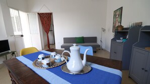 A dining area with a table set for tea, a sofa, and a cabinet. - Villa Camilla in Otranto (Provincia di Lecce)