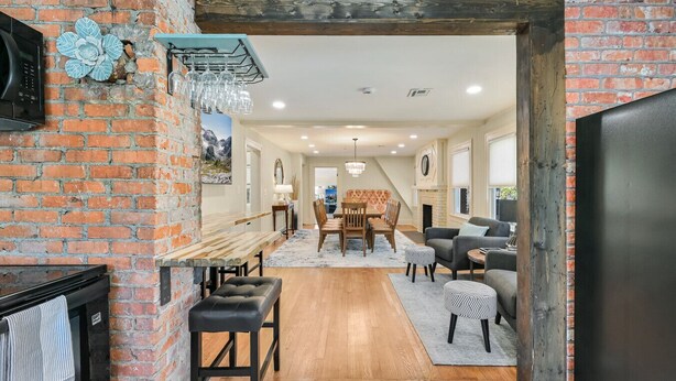 A modern kitchen with a brick wall, a wooden dining table, and a black refrigerator.