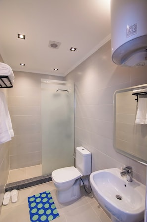 Un baño moderno con inodoro, bidé, lavamanos y cabina de ducha de cristal.