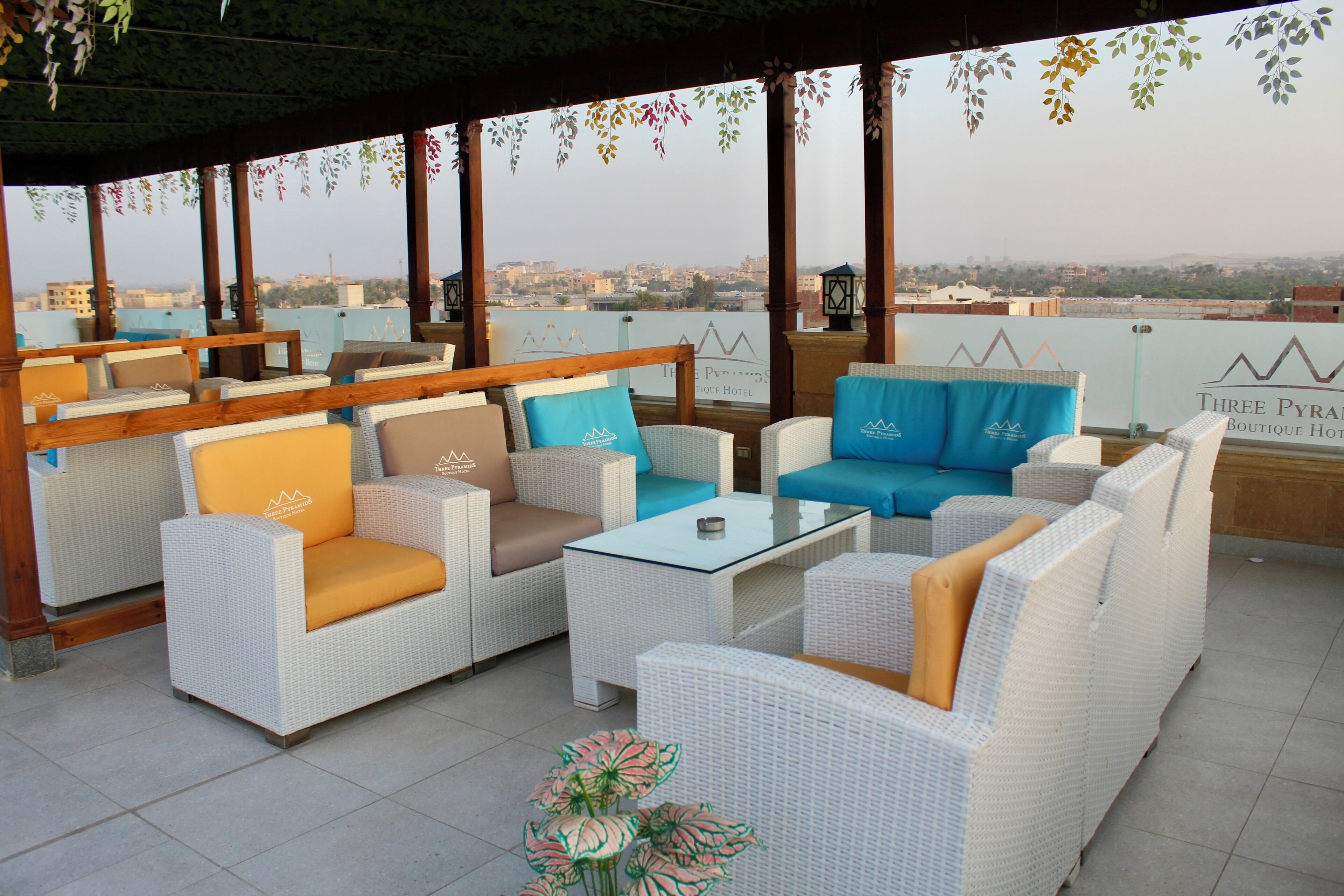 Une terrasse sur le toit, aménagée avec des meubles en osier, une table en verre et offrant une vue sur le paysage urbain.