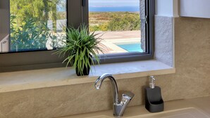 Ein Badezimmer mit großem Fenster, Waschbecken und einem Topf mit Pflanze.