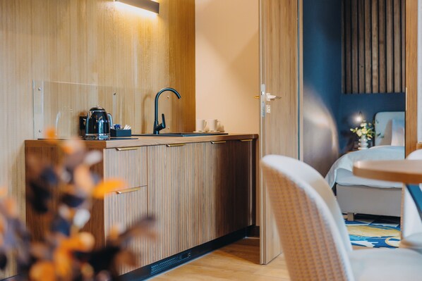 Una habitación de hotel pequeña con kitchenette, una cama y una zona de estar.