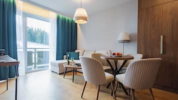 Ein modernes Wohnzimmer mit einer Couch, Sesseln, einem Esstisch und einer Lampe.