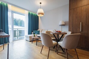 Een moderne woonkamer met een bank, stoelen, een eettafel en een lamp.