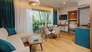 A modern living room with a sofa, dining table, chairs, and a kitchen area with a TV.