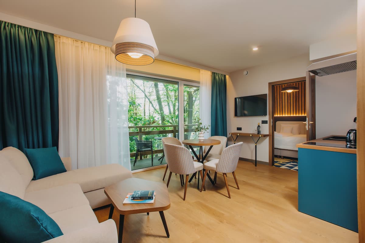 Una sala moderna con sofá, mesa de comedor, sillas y una zona de cocina con televisor.