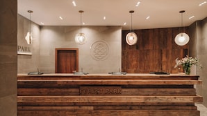 A reception desk with a wooden finish and the name "FOREST PARK" on it. There are three pendant lights above the desk, and a wooden panel wall behind it.