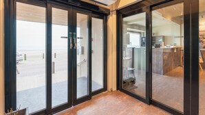 Interior moderno com grandes portas de correr de vidro que dão para uma varanda com vista para o mar.
