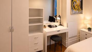 Une chambre à coucher avec un lit, un bureau et une chaise, une armoire et un tableau accroché au mur.