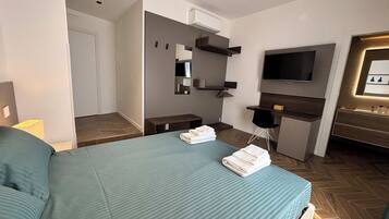 Une chambre d’hôtel avec un lit, un bureau, une télévision et un miroir.