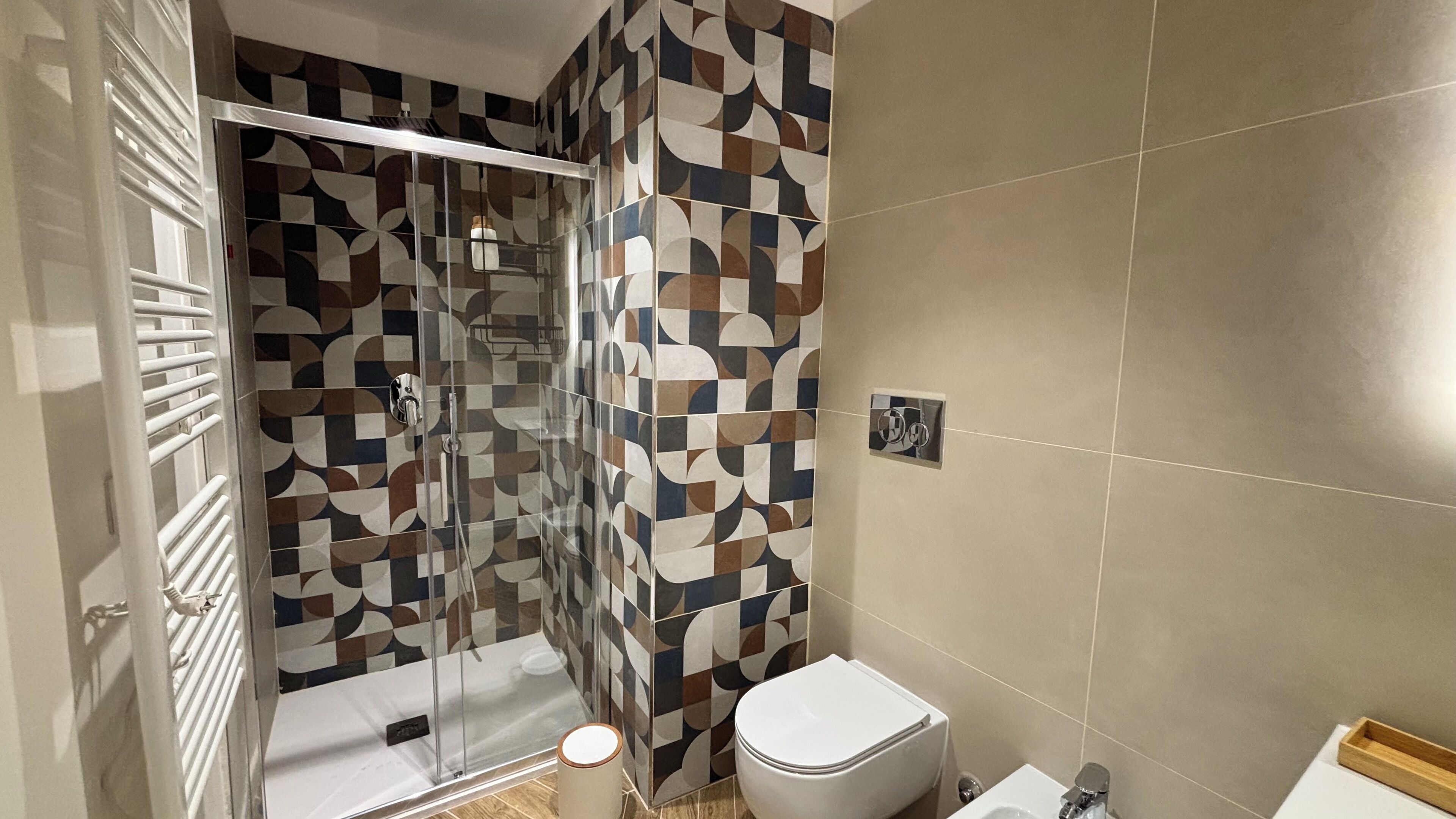 Une salle de bain avec douche, toilettes et un mur décoré de motifs.