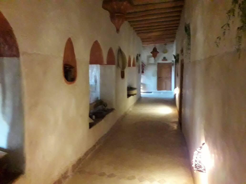 Un corredor estrecho con puertas arqueadas y techo de madera.