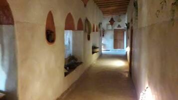 Un corredor estrecho con puertas arqueadas y techo de madera.