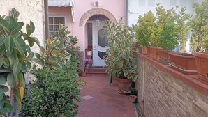 Une petite cour intérieure agrémentée de plantes en pot et une porte donnant accès à un bâtiment.