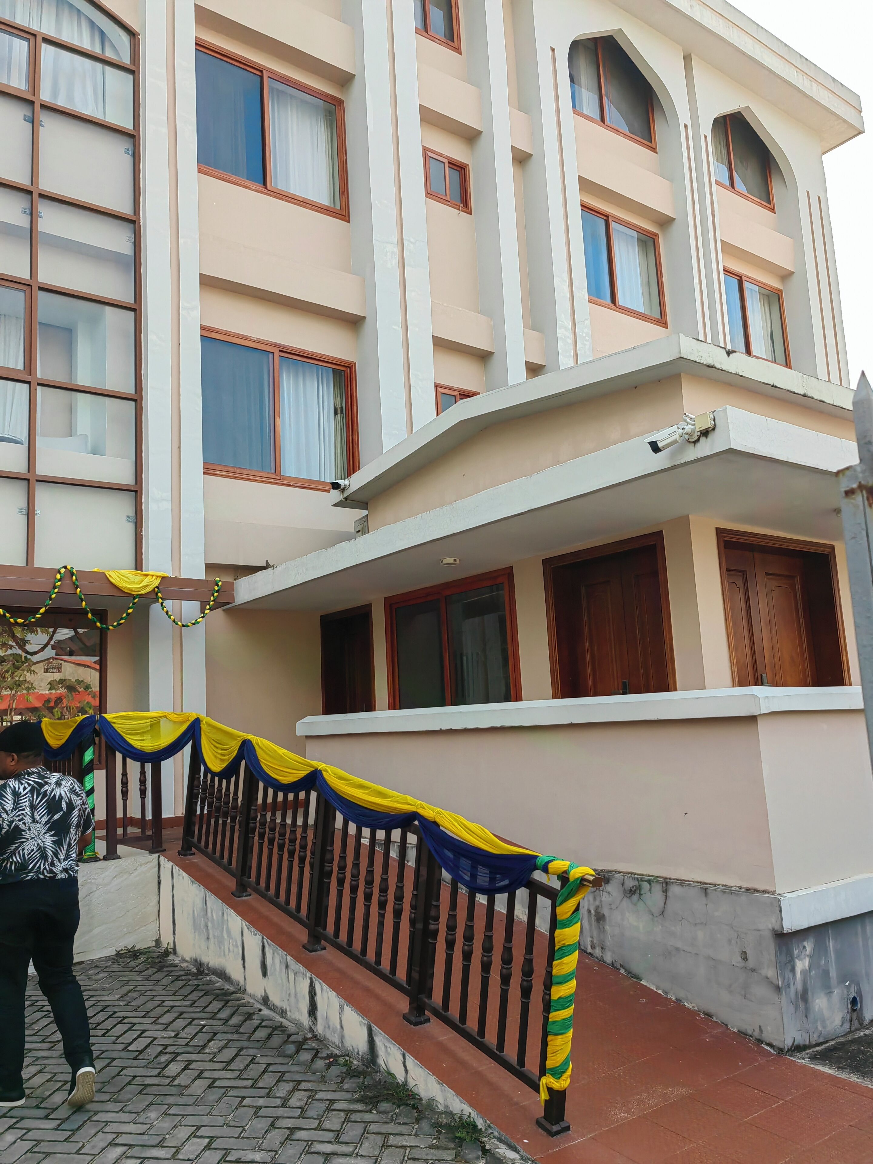 Un edificio de varios pisos con balcones, entrada vigilada y cámara de seguridad.