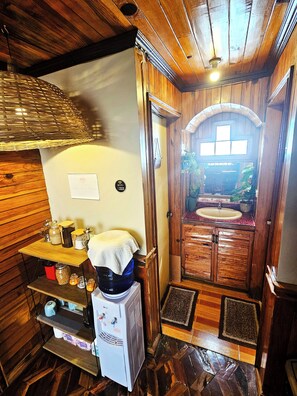 A compact kitchen with wooden cabinets, a water dispenser, and a small sink.