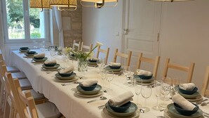 A long dining table set with plates, bowls, and glasses, surrounded by wooden chairs. - Elegant, charming residence with landscaped garden (Jazennes)
