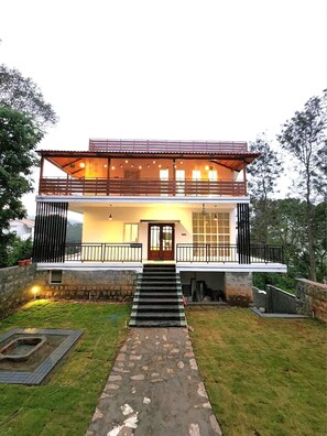 A modern two-story house with a balcony, a front door, and a stone pathway leading to the entrance. - Orion Blu Yercuad  (Yercaud)