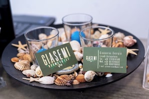 Un plateau contenant des coquillages et deux cartes de visite de l’établissement Giasemi Rooms.
