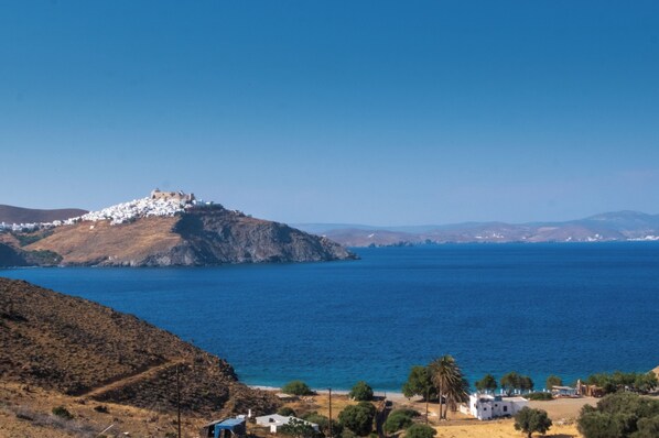 Un paysage côtier avec un bâtiment blanc situé sur une colline, d’où l’on a une vue sur la mer.