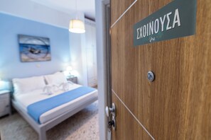 Une chambre d’hôtel avec un lit, une table de chevet, une lampe et une pancarte sur la porte.