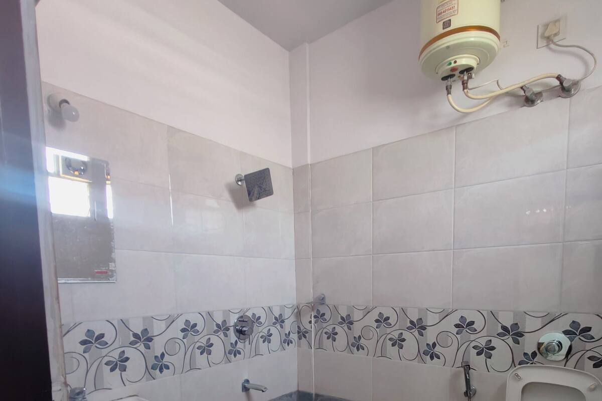 A bathroom with a toilet, sink, shower, and a water heater mounted on the wall.