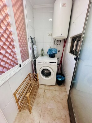 A compact laundry room with a washing machine, a drying rack, and a water heater. - A1089 - Sunny apartment with pool view (Villajoyosa)