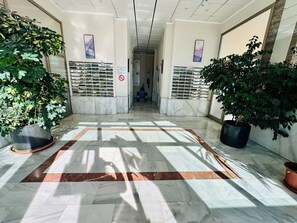 A lobby with marble flooring, potted plants, and a central area with a patterned rug. - A1089 - Sunny apartment with pool view (Villajoyosa)