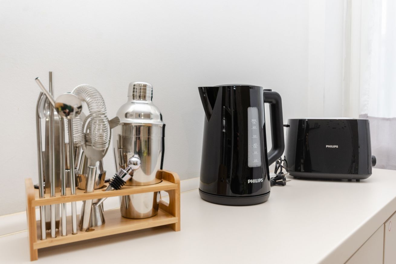 Un plan de travail de cuisine avec une machine à café, un grille-pain et un présentoir contenant divers ustensiles de cuisine.