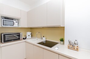 Compact kitchen with microwave, toaster oven, and coffee maker, perfect for meal preparation.