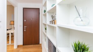 Un couloir avec une porte en bois, des étagères blanches et une plante en pot.