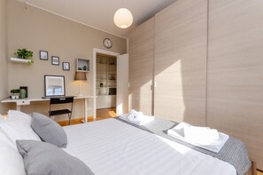 Relax in a serene space with a neatly made bed, desk, and potted plant.