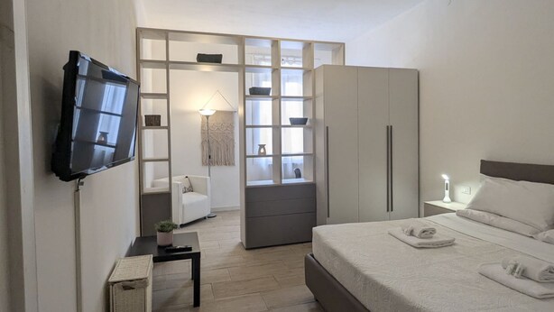 Un dormitorio moderno con cama, televisor, armario y escritorio.