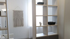 Un interior moderno con un colgador de macramé blanco, una estantería de madera con cestas y una silla blanca.