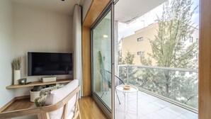 A balcony with a TV, seating, and a view of trees and buildings. - Maximus Design By House and People (Braga)