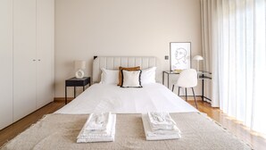 A hotel room with a large bed, a bedside table with a lamp, a desk with a chair, and a window with curtains. - Maximus Design By House and People (Braga)