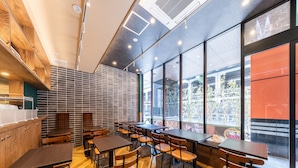 A modern restaurant interior with wooden flooring, metal chairs, and tables. Large windows offer views of the city. - APA Hotel Suidobashi Ekimae (Tokyo)