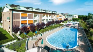 Un hotel con piscina, area salotto all'aperto e giardino curato.