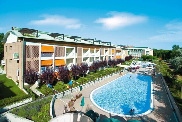 A hotel with a swimming pool, outdoor seating, and a well-maintained garden.